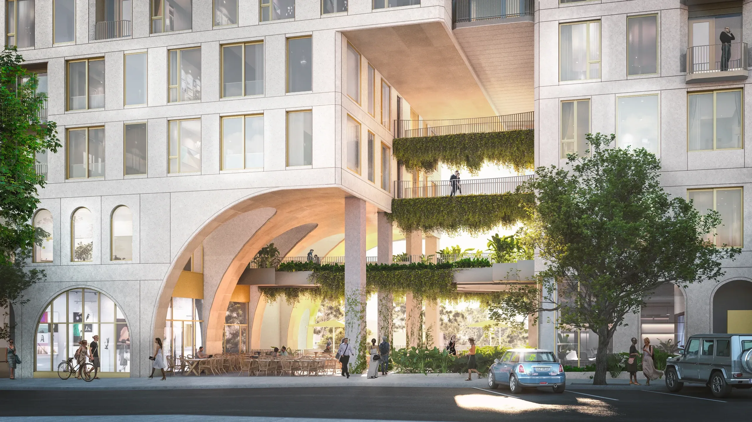 Modern mixed-use building with curved archway entrance, ground-floor retail spaces, and vertical greenery on illuminated upper levels.